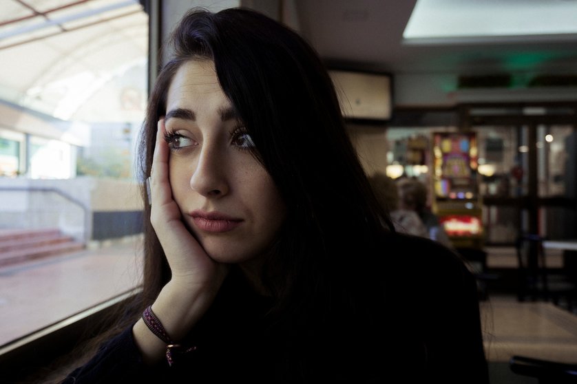 Una joven mira a través de una ventana de una cafetería en Madrid | Sergio Moreno