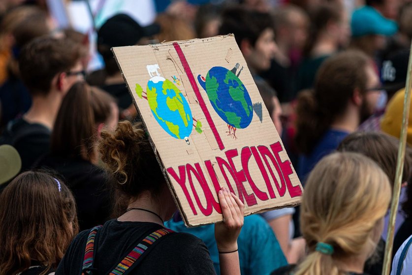 Una manifestante ambientalista sostiene una pancarta contra los combustibles fósiles