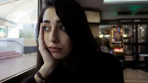 Una joven mira a trav&eacute;s de una ventana de una cafeter&iacute;a en Madrid | Sergio Moreno
