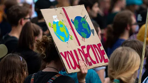 Una manifestante ambientalista sostiene una pancarta contra los combustibles f&oacute;siles